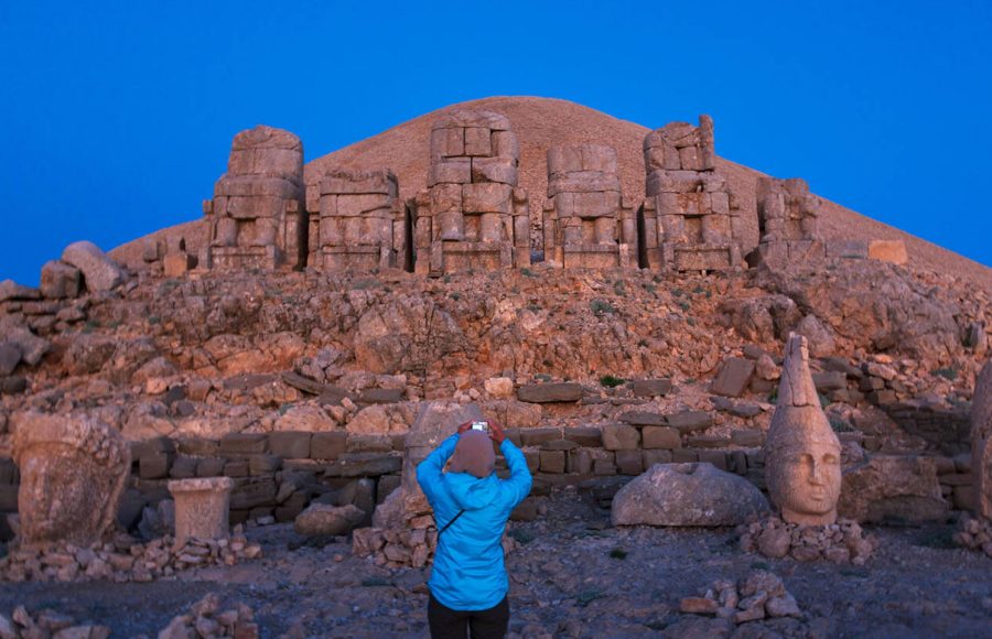 Tourist-photographing-statues-at-sunrise-on-the-eastside-of-the-mountain-Mt-Nemrut-Turkey