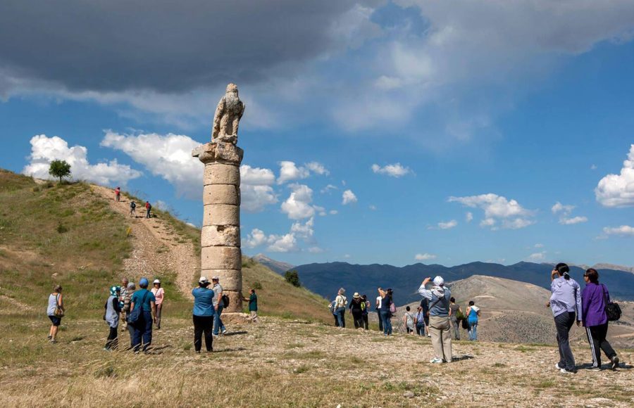 Tourists-admire-a-stone-eagle-statue-sitting-atop-the-southern-column-at-the-ancient-site-of-Karakus-Tumulus-at-Cukurtas-in-Turkiye
