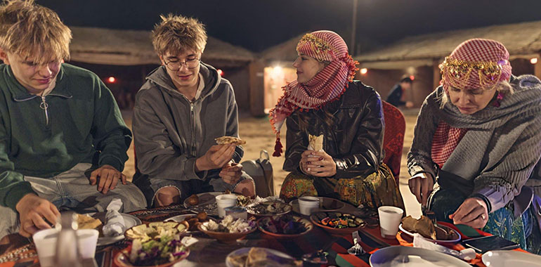 Tourists sharing traditional Emirati meal at Dubai desert camp