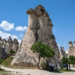Tourists-shelter-under-the-shade-of-a-tree-adjacent-to-a-fairy-chimney-at-Pasabag-in-the-Cappadocia-region-of-Turkey