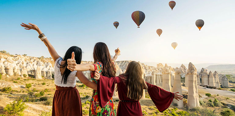 Traveling women looking at air balloons in sky in Cappadocia valley