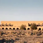 The distinctive, arched mud-brick architecture of the View Of Market Hassan Fathy Designed Village Kharga Oasis Egypt, showing the long, low market building against the clear desert sky.
