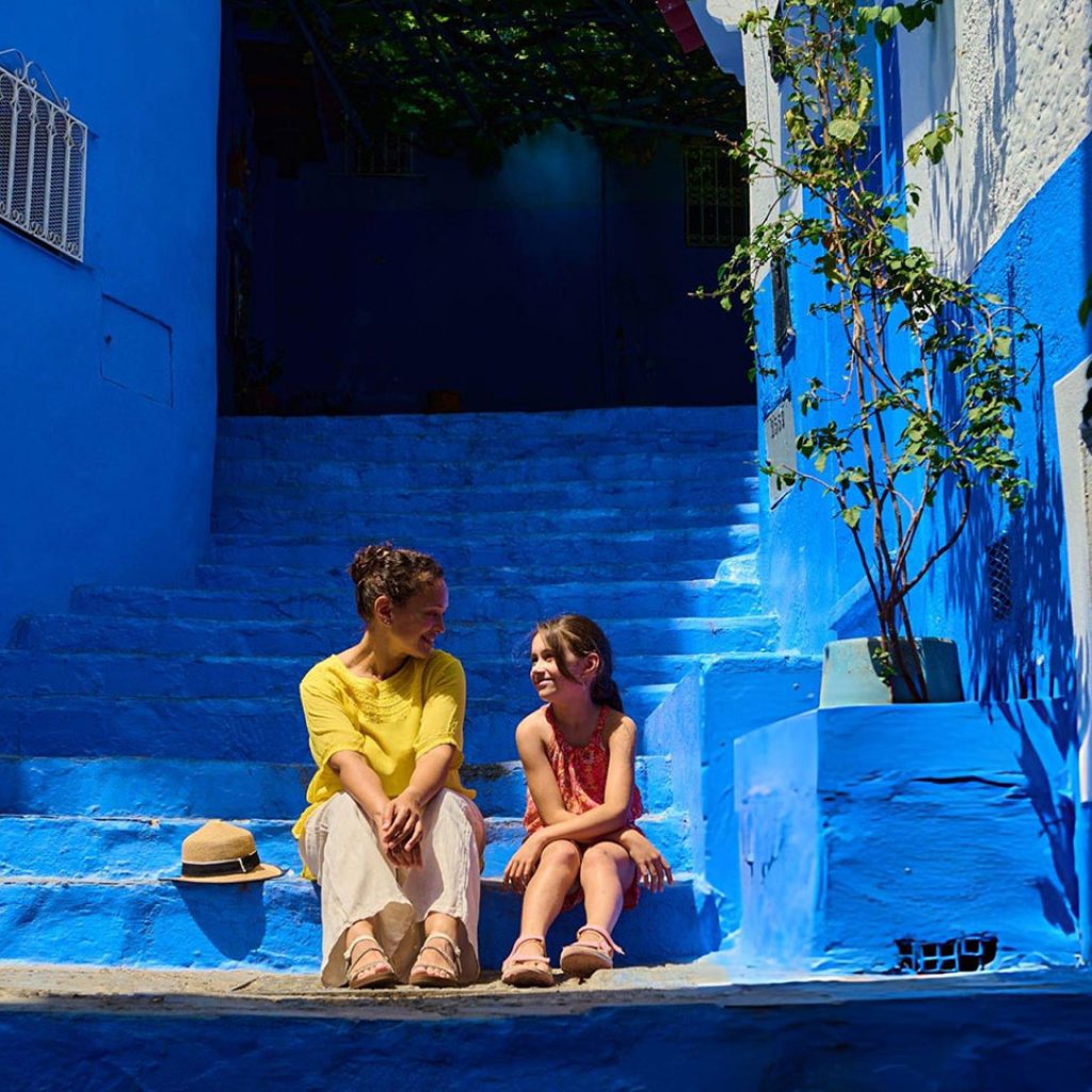 Woman and girl sitting on blue stairs in Chouchaen enjoying travel and warm conversation