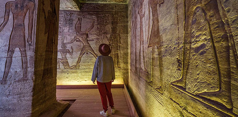 Woman Looking At The Ancient Colorful Carved Paintings On Walls Inside The Temple Of Nefertari Abu Simbel Aswan Egypt
