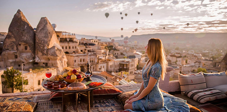 Woman relaxing in Goreme National Park in Cappadocia with hot air ballons in the back ground 1