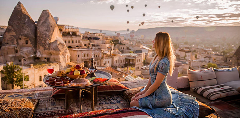 Woman relaxing in Goreme National Park in Cappadocia with hot air ballons in the back ground