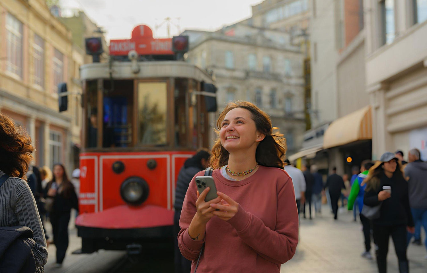 Woman using smartphone walking near the tram in Istanbul enjoing her planning trip to turkey
