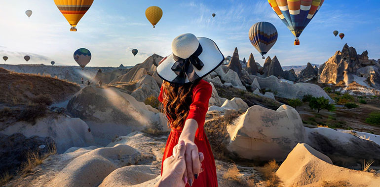 Women tourists holding man hand and leading him to hot air balloons in Cappadocia Turkey