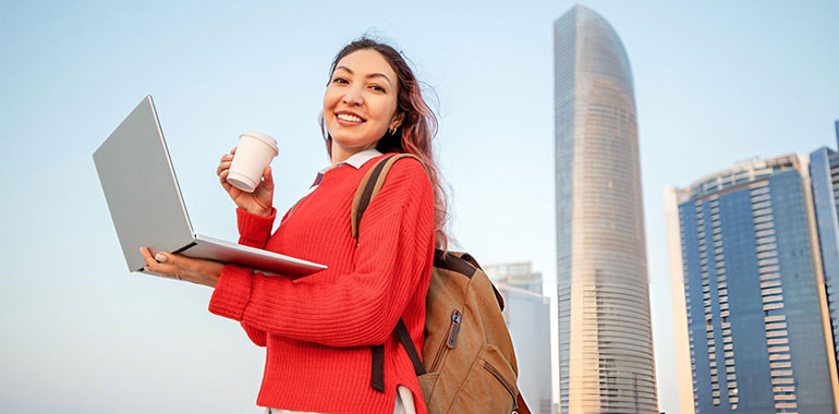 Young student enjoying a coffee while working on her laptop in Abu Dhabi