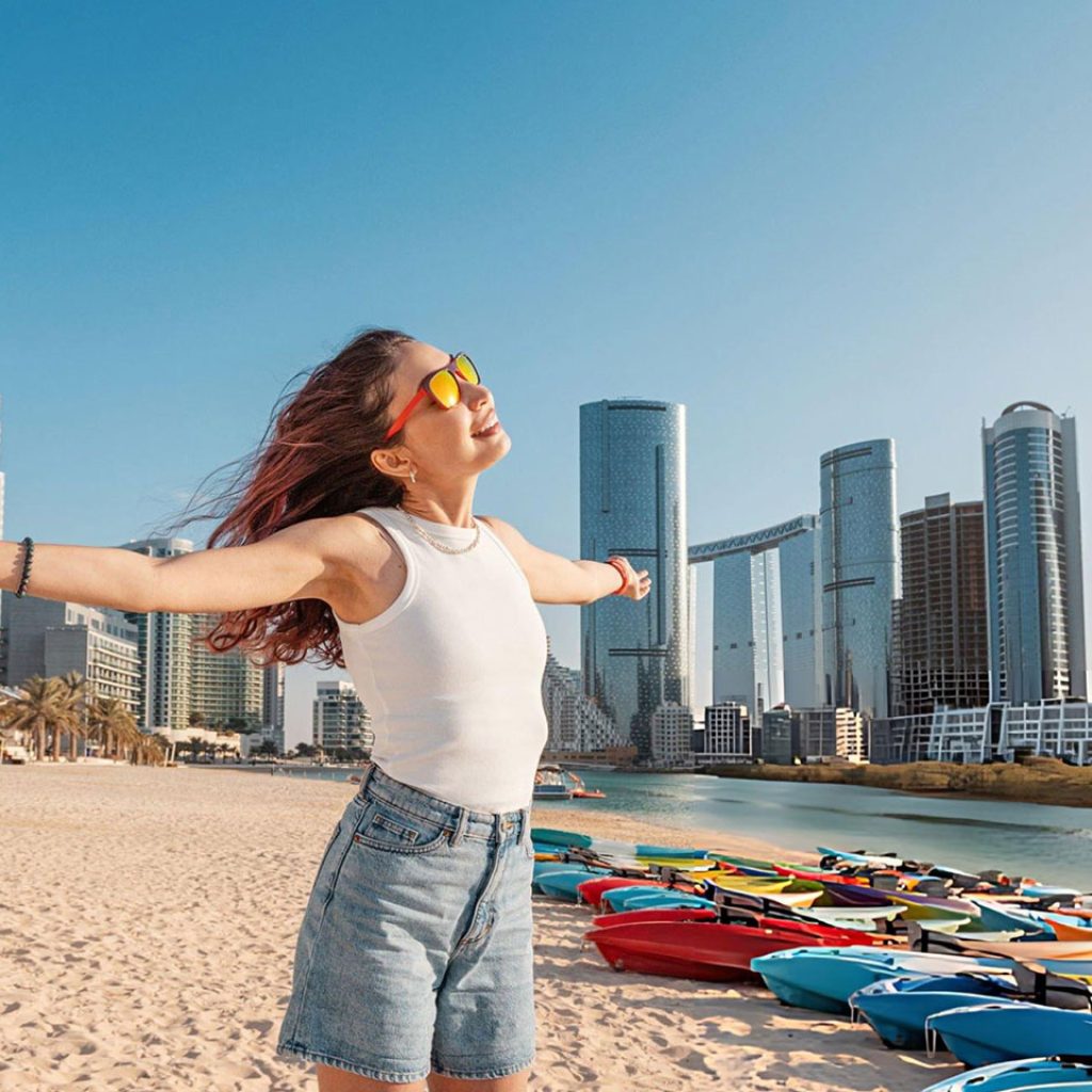 Young woman enjoying freedom on the beach in Abu Dhabi United Arab Emirates with open arms and colorful kayaks