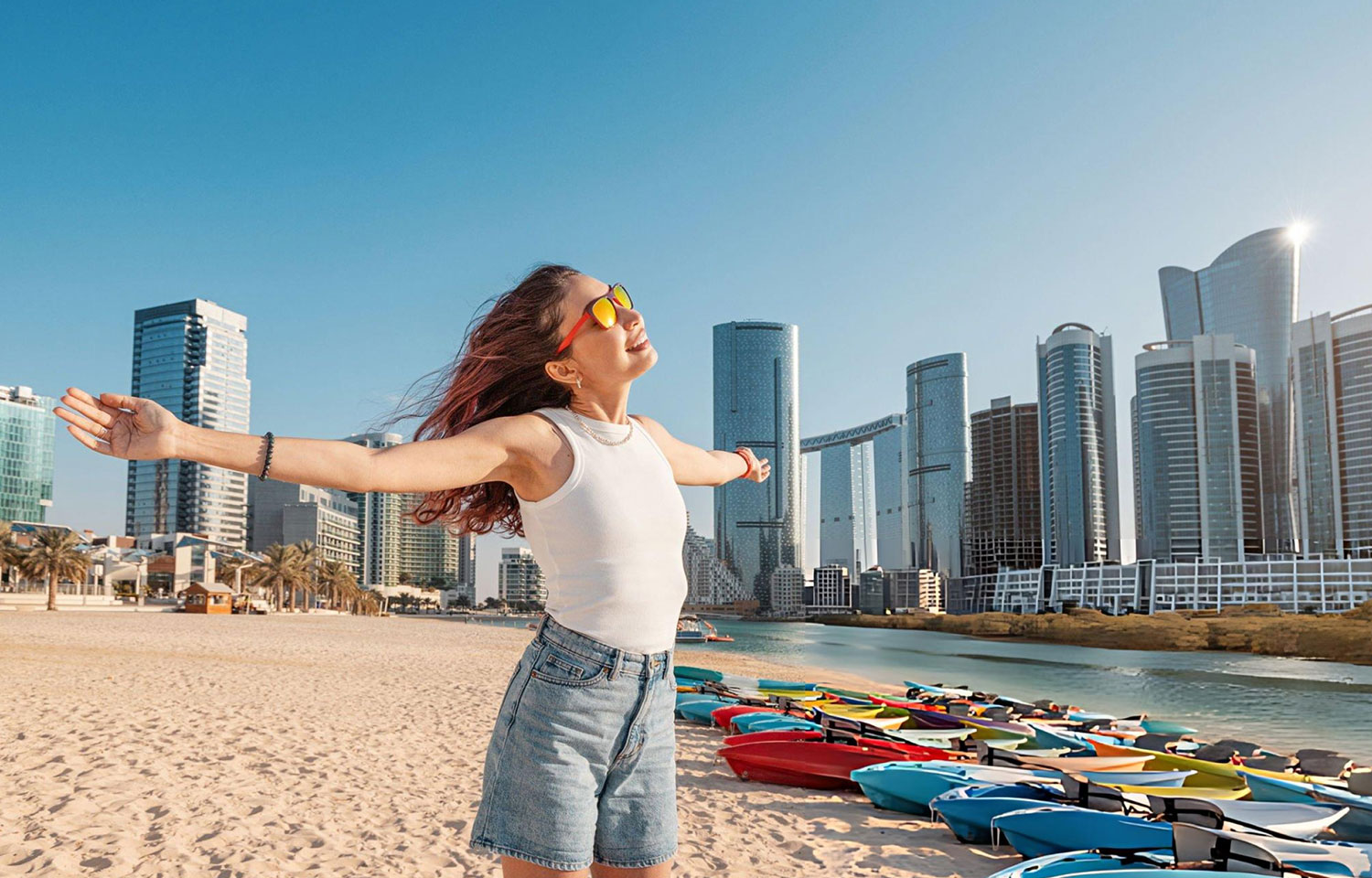 Young woman enjoying freedom on the beach in Abu Dhabi United Arab Emirates with open arms and colorful kayaks