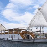 Side view of the white Zekrayaat Dahabiya sailing with two large white lateen sails.