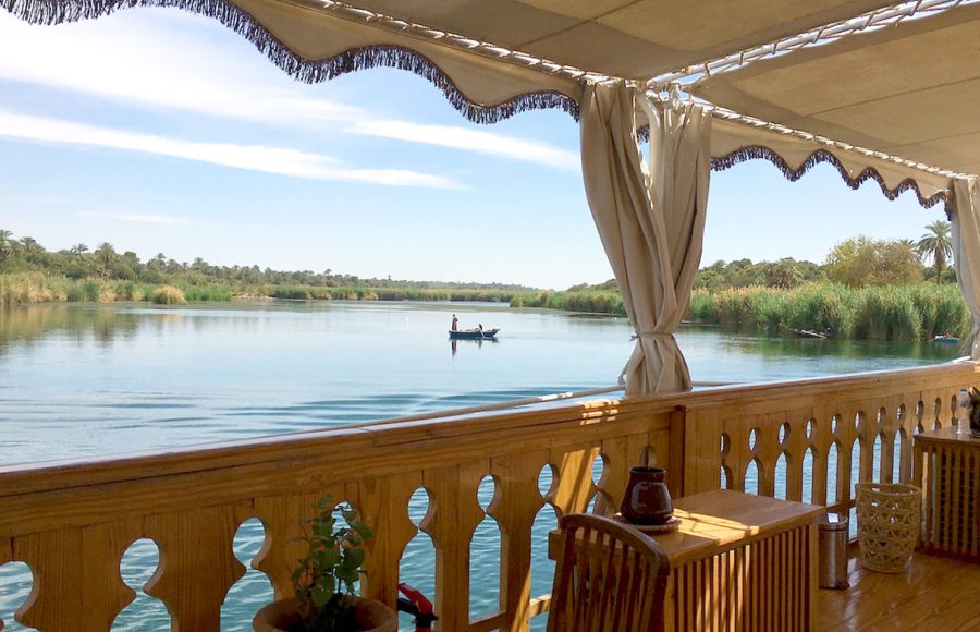 View of the Nile River through the wooden railing of the Dahabiya’s upper deck.