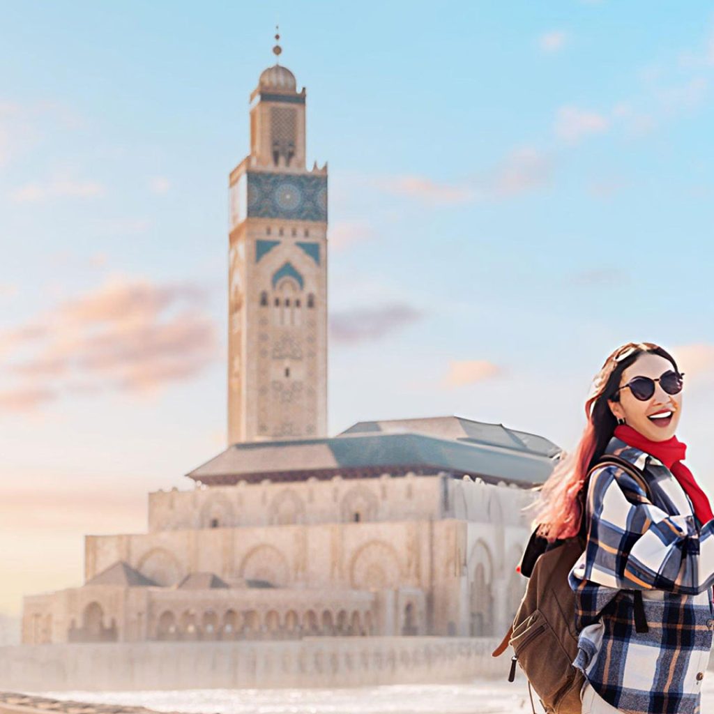 a tourist capturing the stunning Hassan II Mosque by phone at sunset surrounded by the vibrant atmosphere of Casablanca