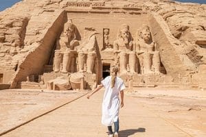 A woman walking towards the massive facade of the Abu Simbel Temple, representing an Egypt overland tour package.