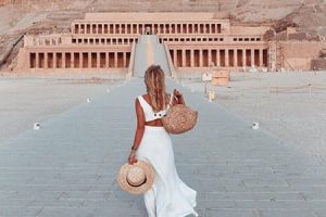 Woman walking towards the impressive terraced architecture of the Temple of Hatshepsut in Egypt.