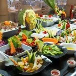 Breakfast buffet on cruise ship with pastries, fresh fruit, and carved decorative pumpkins.