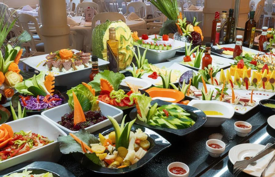 Breakfast buffet on cruise ship with pastries, fresh fruit, and carved decorative pumpkins.