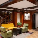 Main entrance and seating area with wooden stairs and modern furniture on the MS Commodore Nile Cruise boat.