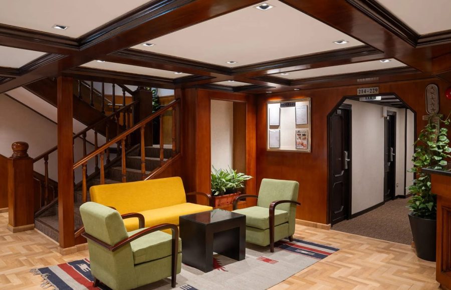 Main entrance and seating area with wooden stairs and modern furniture on the MS Commodore Nile Cruise boat.