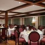 Formal dining restaurant with round tables and red chairs on the MS Commodore Nile Cruise boat.