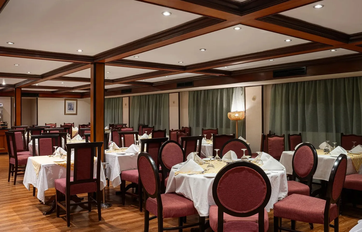 Formal dining restaurant with round tables and red chairs on the MS Commodore Nile Cruise boat.