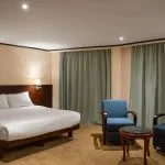 Comfortable suite with a large bed and blue armchairs on the MS Commodore Nile Cruise boat.