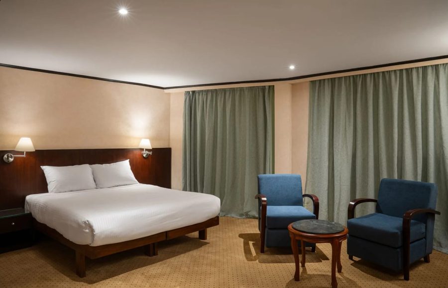 Comfortable suite with a large bed and blue armchairs on the MS Commodore Nile Cruise boat.