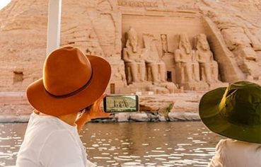 People on a boat viewing the magnificent Abu Simbel Temple from the water, part of comprehensive Egypt tour packages.