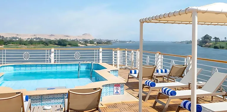 A Nile Cruise Sun Deck With A Small Pool, Loungers, And River View.
