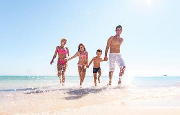 A happy family running and splashing on the beach, the perfect end to a 10 day Egypt itinerary beach and culture.