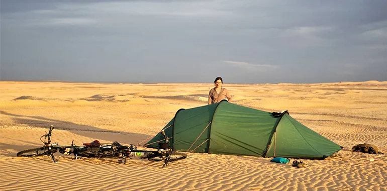 Girl Standing Next To Tent With Bicycles In Golden Evening Light In Western Desert Of Egypt.jpg
