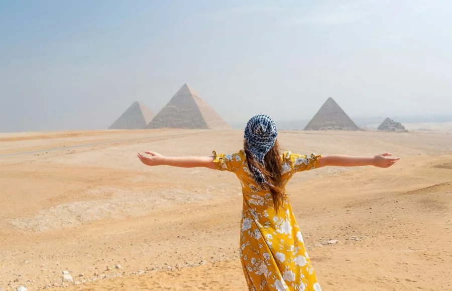 A female with long brown hair facing the three majestic Giza Pyramids in her 6 days Cairo and Hurghada Holiday.
