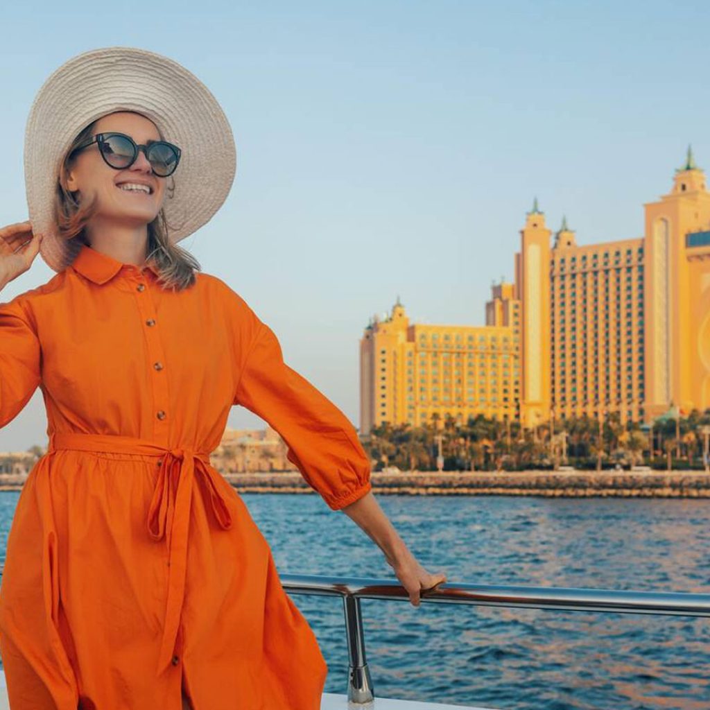 Happy Elegant Woman In Orange Dress On Yacht With Atlantis Hotel In Background Dubai United Arab Emirates