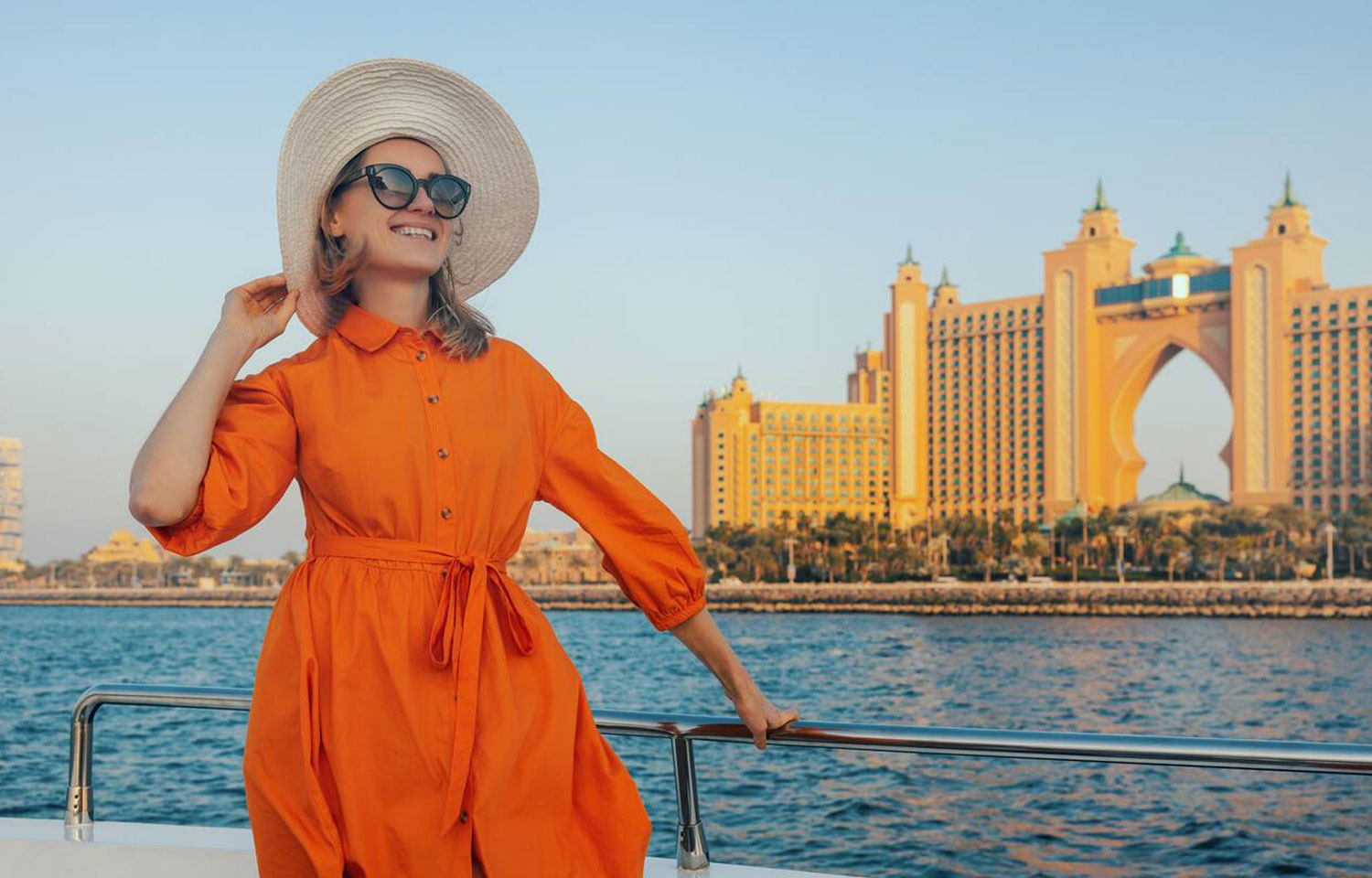 Happy Elegant Woman In Orange Dress On Yacht With Atlantis Hotel In Background Dubai United Arab Emirates