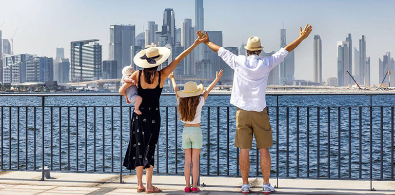 Happy Family Of Four Looks At The Urban Skyline Of Dubai Uae During Their City Vacations