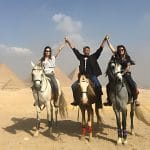 Travelers raising their hands during an exciting horseback ride pyramids excursion