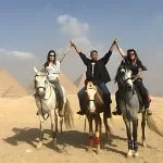 Travelers raising their hands during an exciting horseback ride pyramids excursion