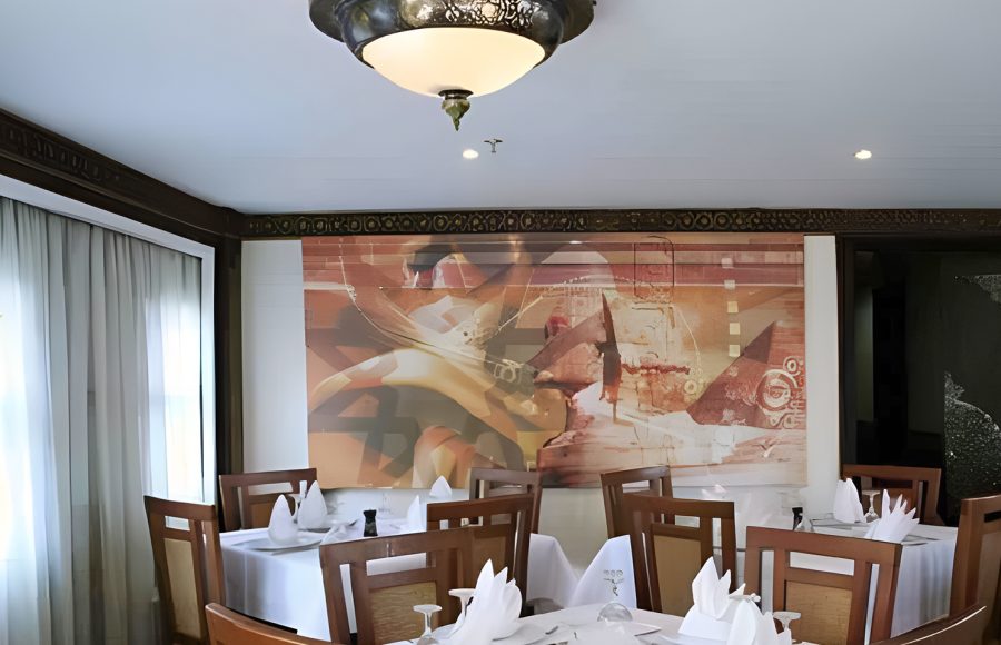 Elegant indoor dining room with white-clothed tables and a large abstract wall mural.