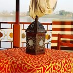 Close-up of a traditional metal lantern on a red and gold patterned table on a Nile cruise boat deck.
