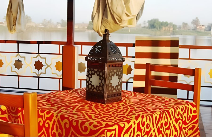 Close-up of a traditional metal lantern on a red and gold patterned table on a Nile cruise boat deck.