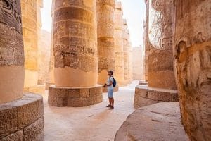 A man looking up at the towering columns of Karnak Temple, part of standard Nile Cruise trip.