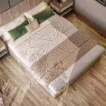 Overhead view of a modern king-sized bed with green and beige bedding, wood flooring, and a round chair.