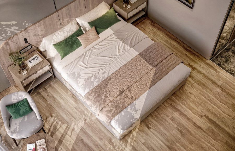 Overhead view of a modern king-sized bed with green and beige bedding, wood flooring, and a round chair.