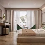 Luxury cruise cabin with a king-sized bed, vanity desk, green armchairs, and a view of sailboats from the window.