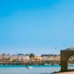 A kite surfer moving quickly through the shallow blue water near a beach.
