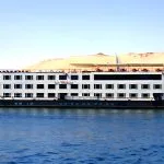 A Nile Cruise ship sailing past sandy riverbanks, part of the best Egypt all inclusive tour.