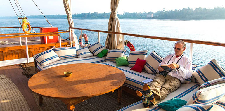 Man Relaxing And Reading On The Deck Of A Nile Dahabiya Boat On The Nile River