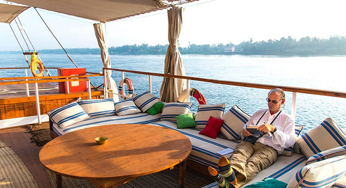 Man Relaxing And Reading On The Deck Of A Nile Dahabiya Tourist Boat On The Nile River