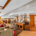 Cruise ship lobby with mezzanine, gift shop displays, and a massage treatment sign.